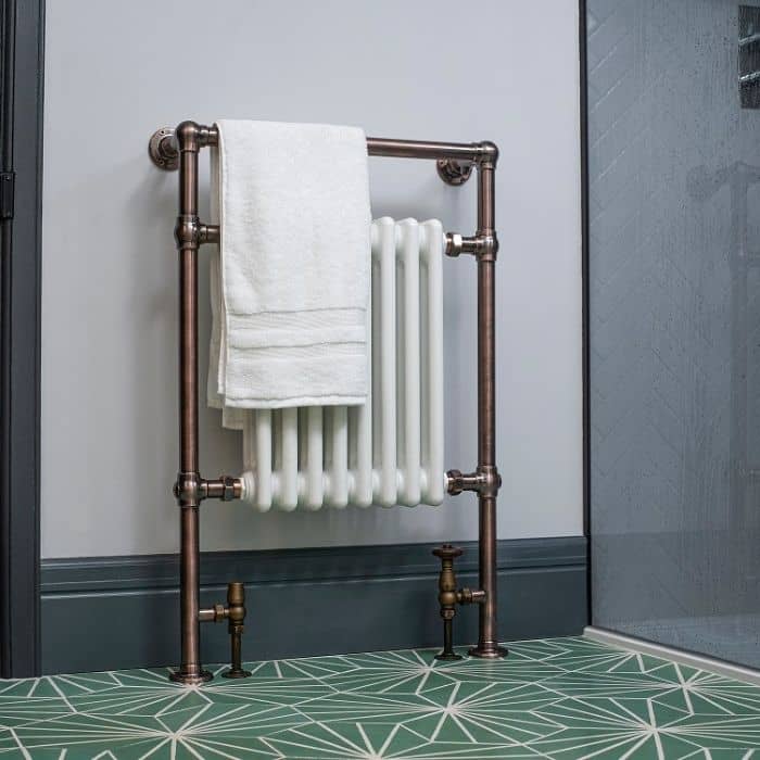bronze heated towel rail with white columns in a blue bathroom