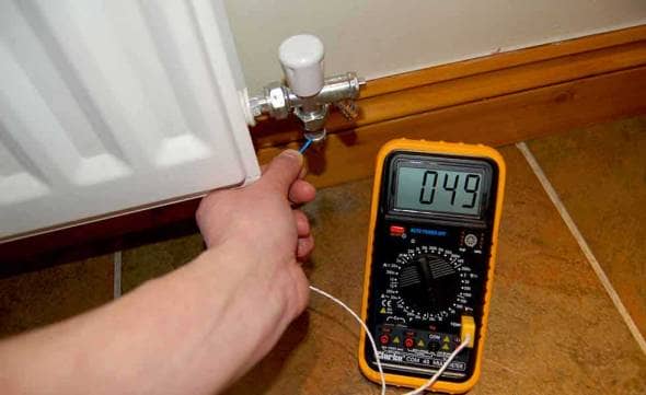 Man taking temperature near a radiator with an electronic thermometer