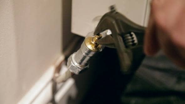 Man turning lockshield valve on radiator