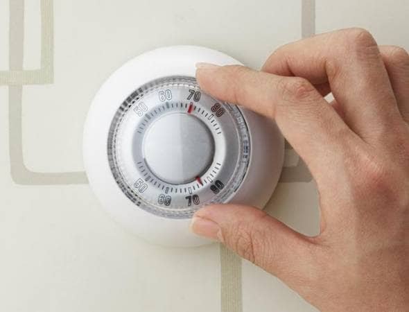 woman's hand turning off a thermostat