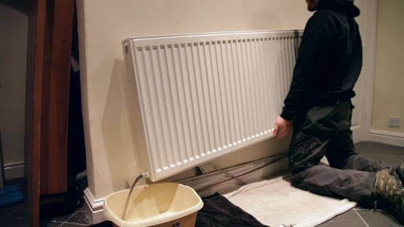 Man pouring water from a radiator into a washing up bowl