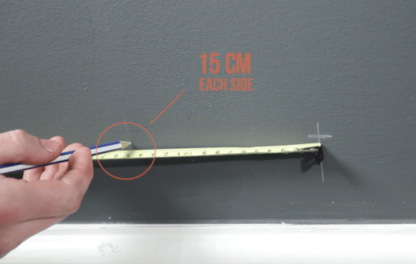 15cm being marked on a wall with a tape measure and a pencil