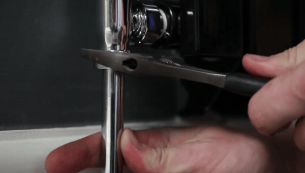 A spanner being used to tighten a nut at the bottom of a radiator valve