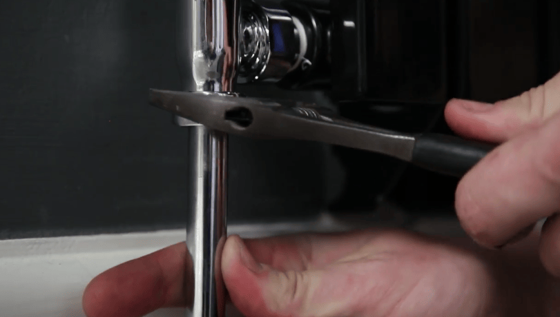 A spanner being used to tighten a nut at the bottom of a radiator valve