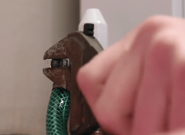 Plumber using a spanner to turn the valve and drain water from a radiator