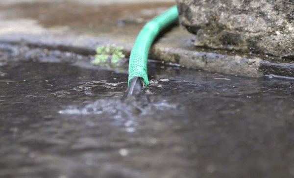 Water being drained from a hosepipe into the street