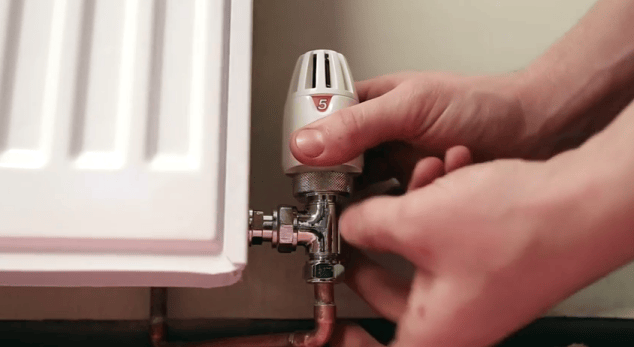 a plumber installing a TRV to a radiator to improve radiator performance