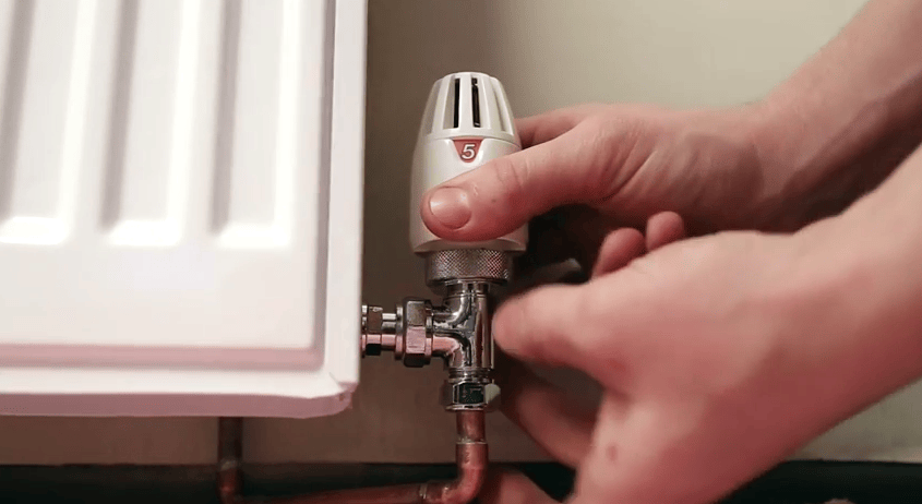a plumber installing a TRV to a radiator to improve radiator performance a plumber installing a TRV to a radiator to improve radiator performance