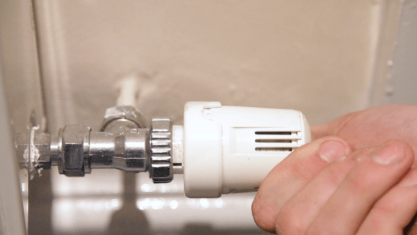 A hand turning a trv on a radiator