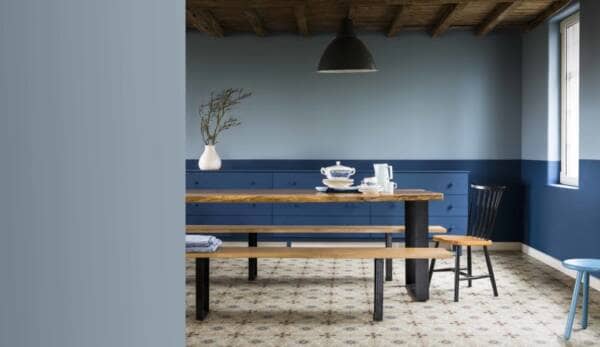 A dining room painted blue with a long dining table and benches