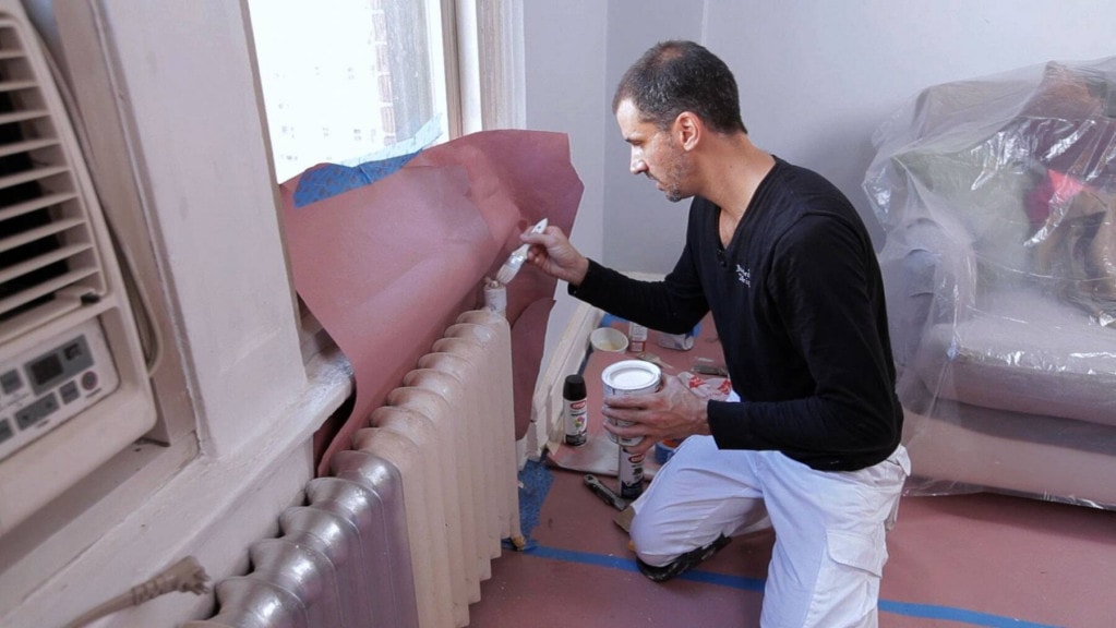 Paint a radiator A man applying primer to a radiator before painting it in full