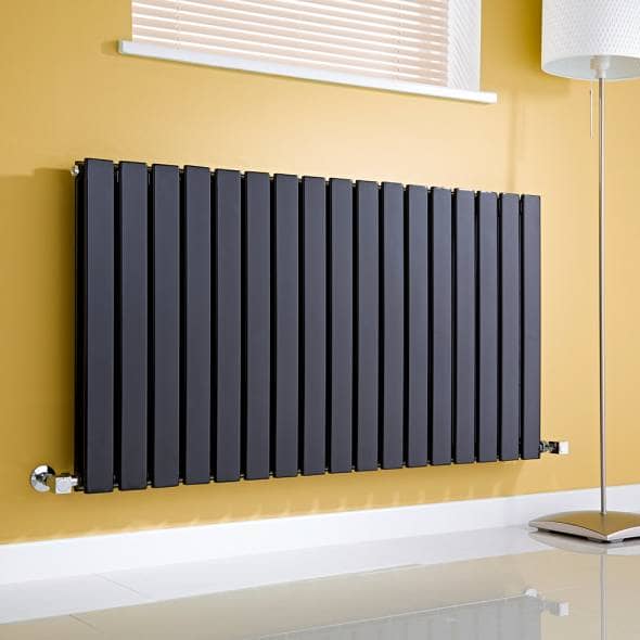 Anthracite Milano Alpha Radiator on a wall in a lounge next to a window and a lamp - changing a radiator