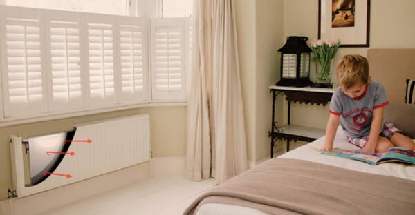 A boy reading on a bed while a radflek radiator reflector works in the background