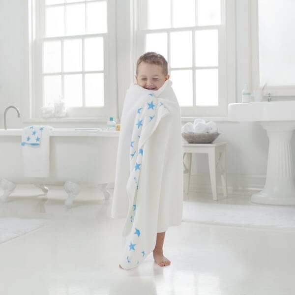 kid in white and blue towel getting out of the bath smiling