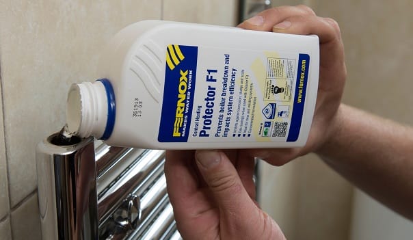 Inhibitor being poured into heated towel rail man adding radiator inhibitor to a heated towel rail