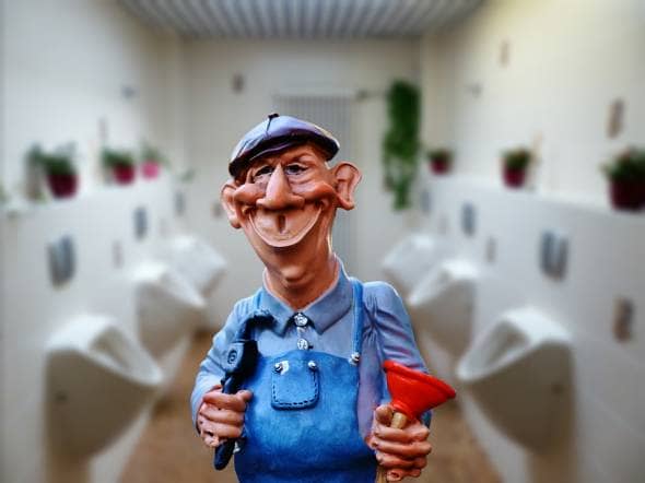 Plumber standing next to a load of urinals in a bathroom