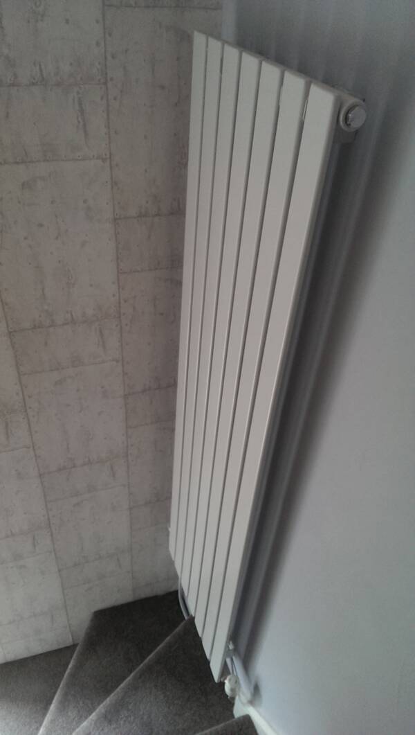 Tall white vertical radiator at bottom of stairs Tall vertical radiator at the bottom of the stairs