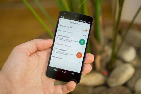 A hand holding a mobile phone showing the Hive heating app from British Gas A hand holding a mobile phone showing the Hive heating app from British Gas