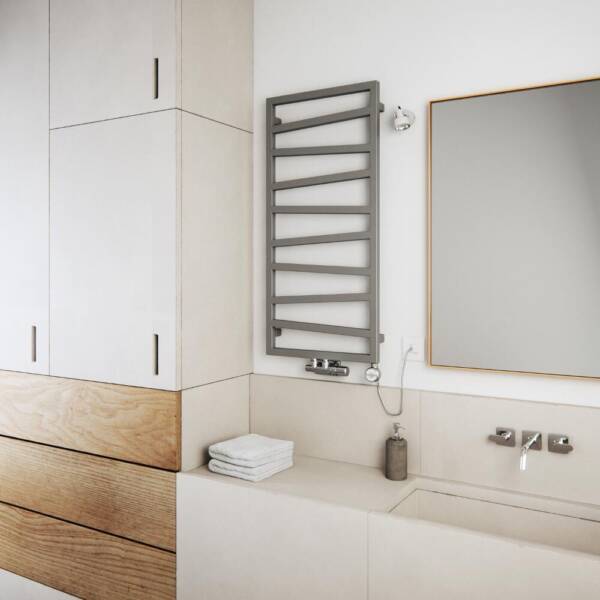 A silver Terma ZigZag dual fuel towel radiator in a bathroom next to a mirror A silver Terma ZigZag dual fuel towel radiator in a bathroom next to a mirror