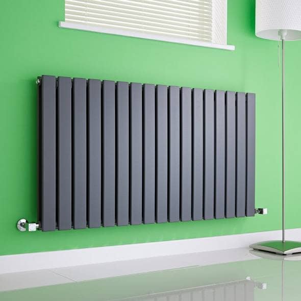 An anthracite grey milano alpha radiator on a green wall in a sitting room