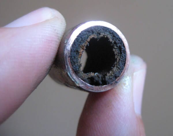 a picture of fingers holding a pipe that is filled with sludge and sediment a picture of fingers holding a pipe that is filled with sludge and sediment