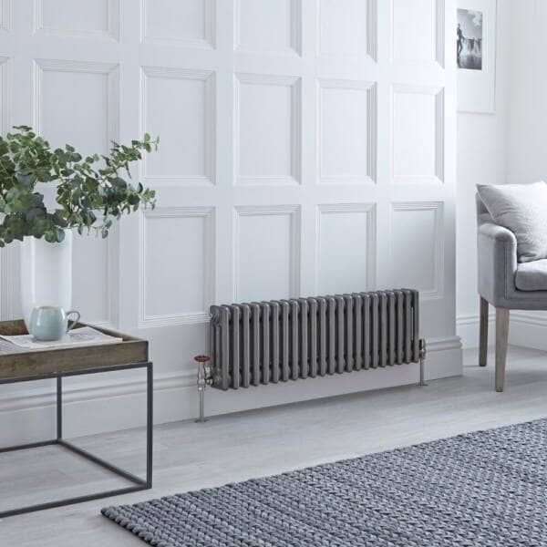 raw metal milano windsor cast iron style radiator on a white panelled wall in a sitting room