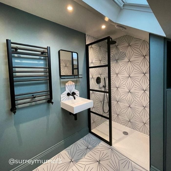 modern black ladder heated towel rail in a green bathroom