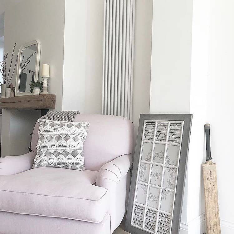 white vertical column radiator behing a pink armchair