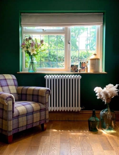 white column radiator on a green wall