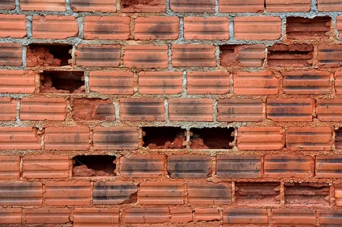 Red brick wall with multiple bricks missing
