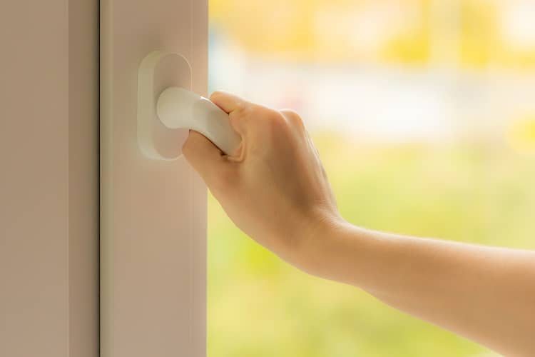 A woman opeing a window to ventilate her home