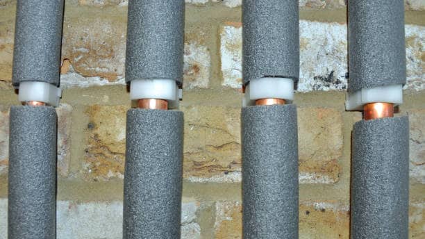 Four copper water pipes in grey foam insulation