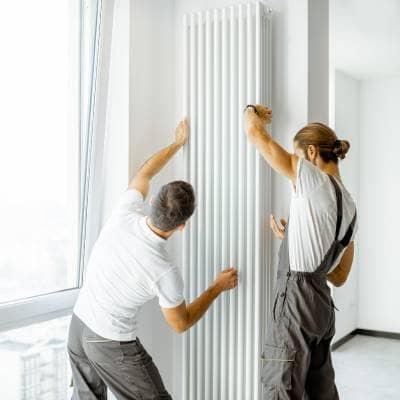 two men installing a vertical central heating radiator