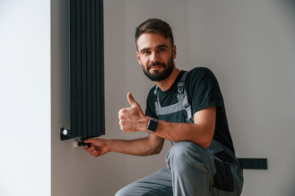 a tradesperson installing a radiator and giving a thumbs up