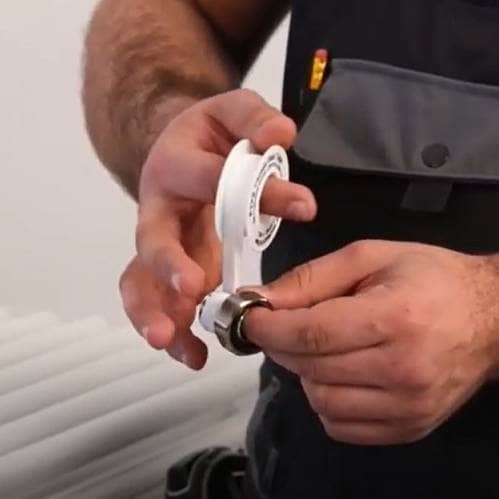 hands wrapping ptfe tape around a radiator valve