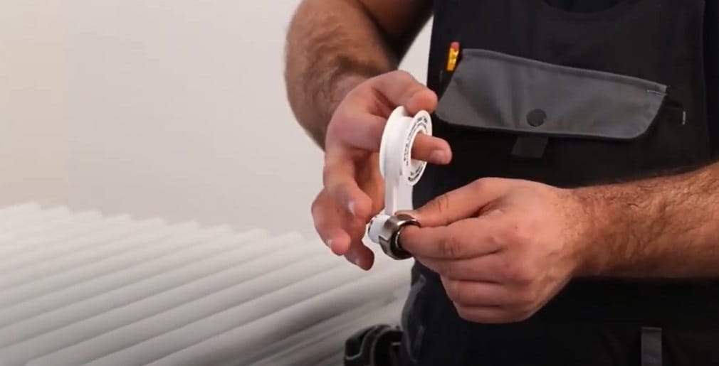 hands wrapping ptfe tape around a radiator valve