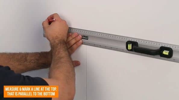 hand drawing a line on the wall with a pencil