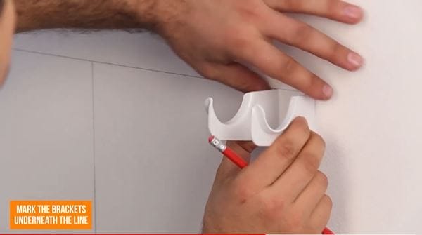 hands holding a radiator bracket on a wall