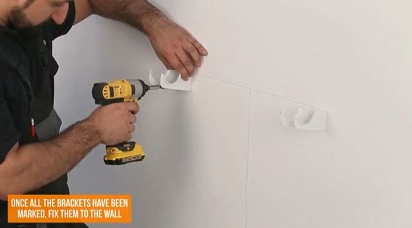 man drilling a hole into a wall