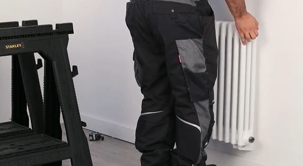 man hanging a radiator on a wall