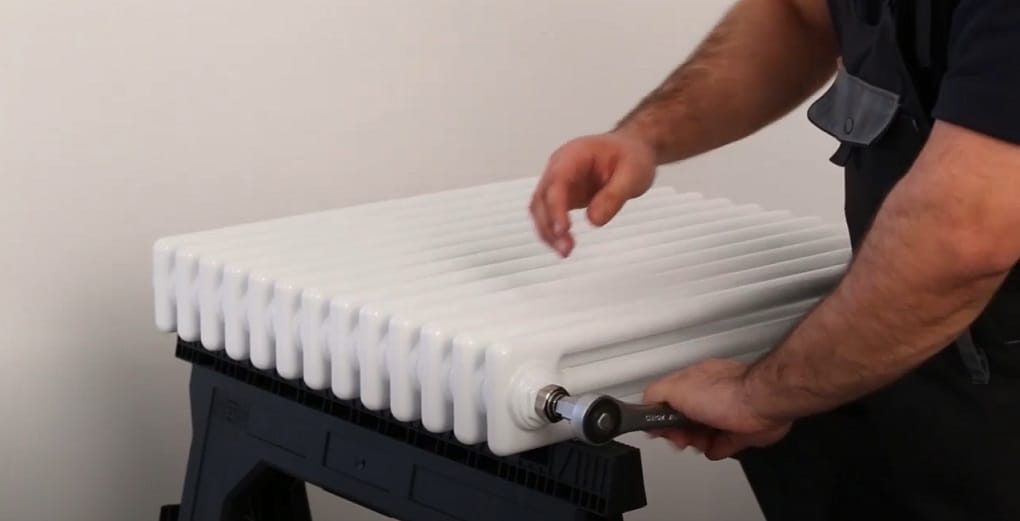 hand turning a radiator spigot with a spanner