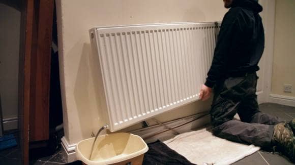 A man tipping a domestic radiator to remove water from the inside