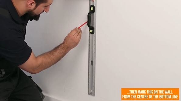 man marking a line on a wall with a pencil