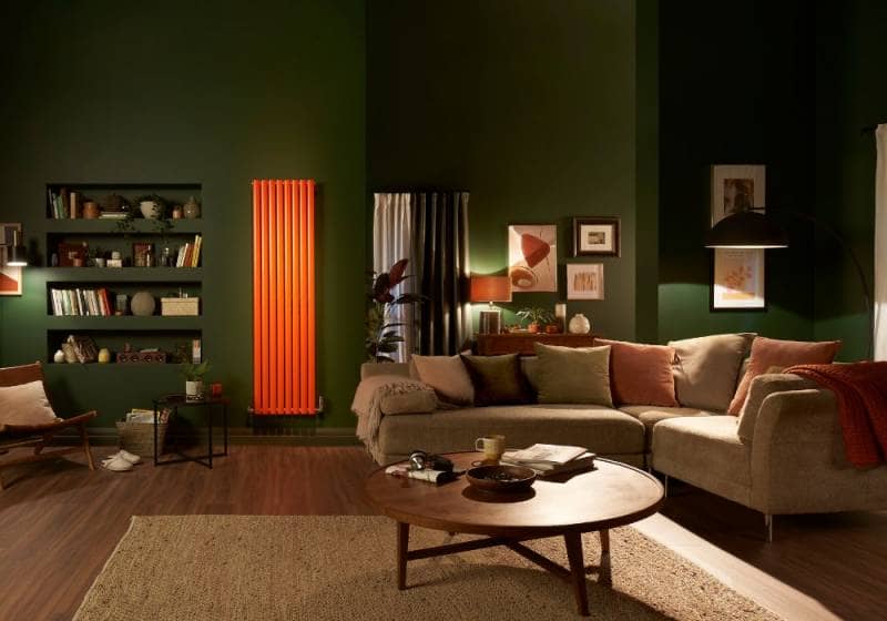 orange radiator in a green living room with gallery wall