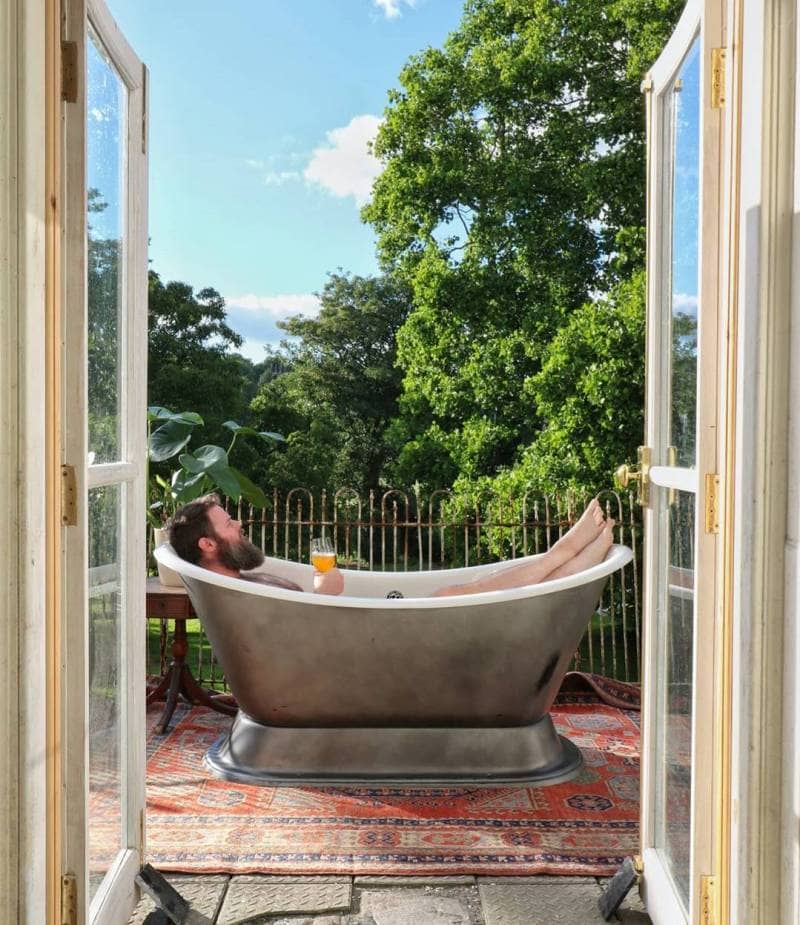 man sat in a bath on balcony