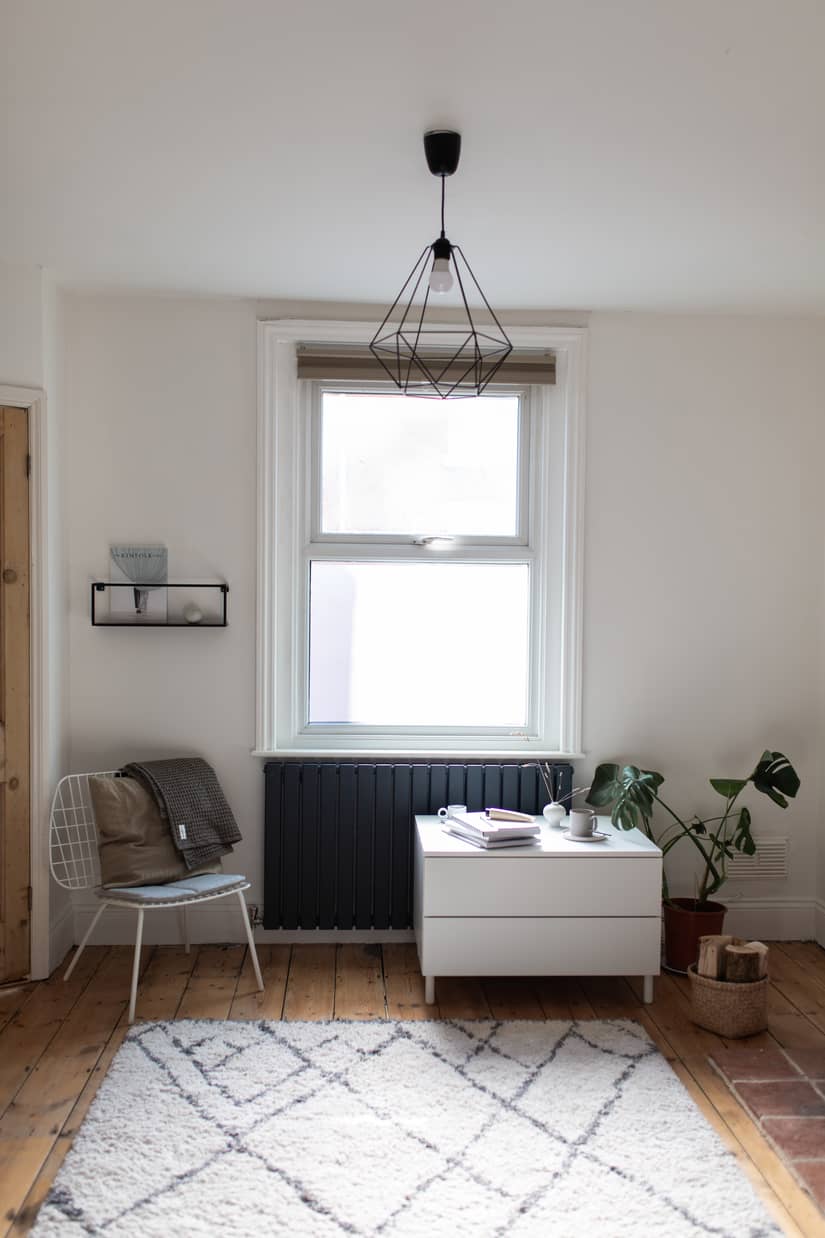 Anthracite radiator beneath window in a Nordic style living room