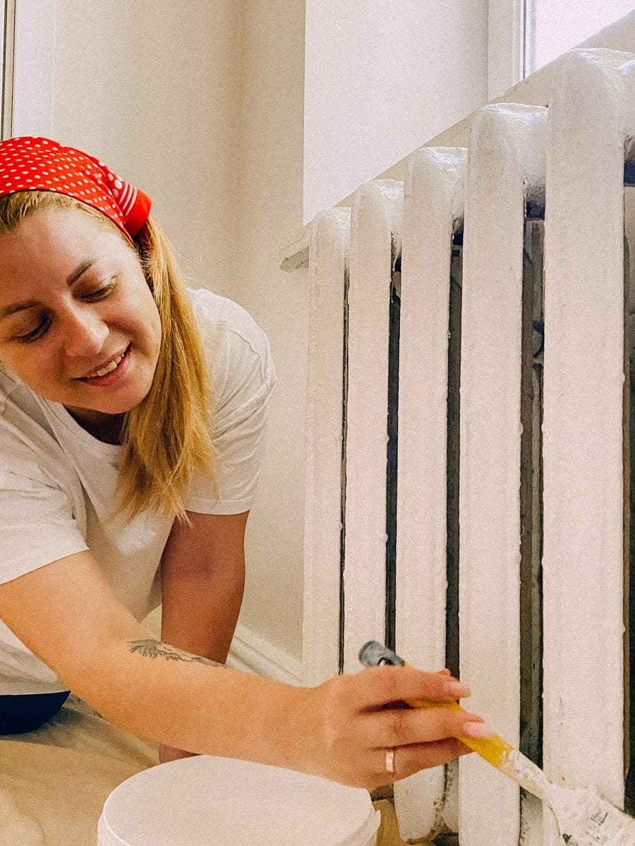Woman painting radiator with white brush Woman painting radiator with white brush