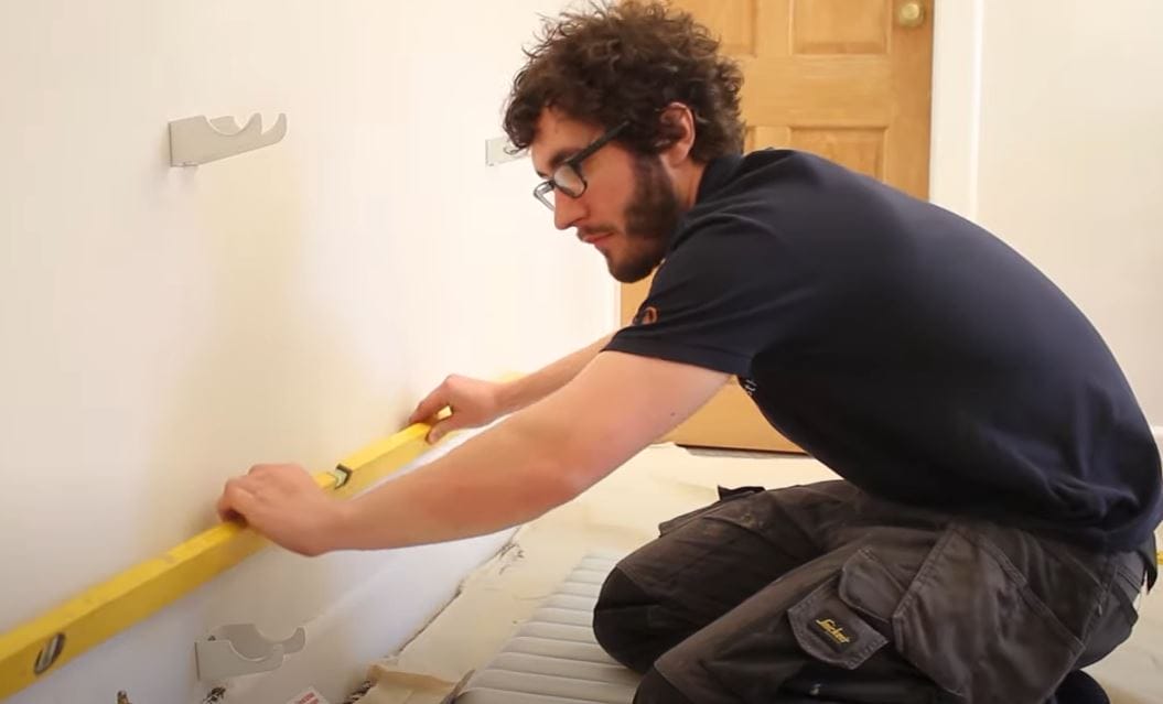 a heating engineer checking the level of replacement radiator brackets