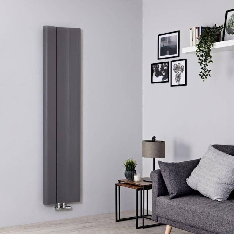 Milano Solis anthracite aluminium single panel vertical designer radiator on light wall nearby multiple framed art and a shelf above a grey lamp and grey settee with cushions