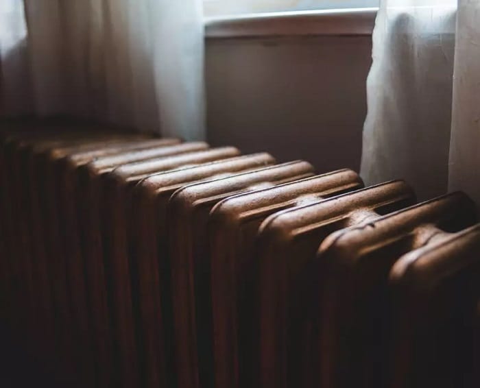 Close up shot of top of copper cast iron radiator beneath window sill